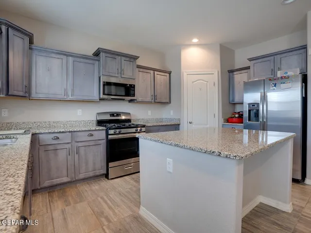 a kitchen with granite countertop a sink stainless steel appliances and white cabinets