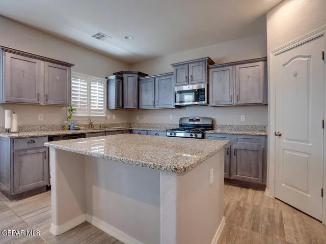 a kitchen with stainless steel appliances granite countertop a stove a sink dishwasher and a refrigerator with wooden cabinets