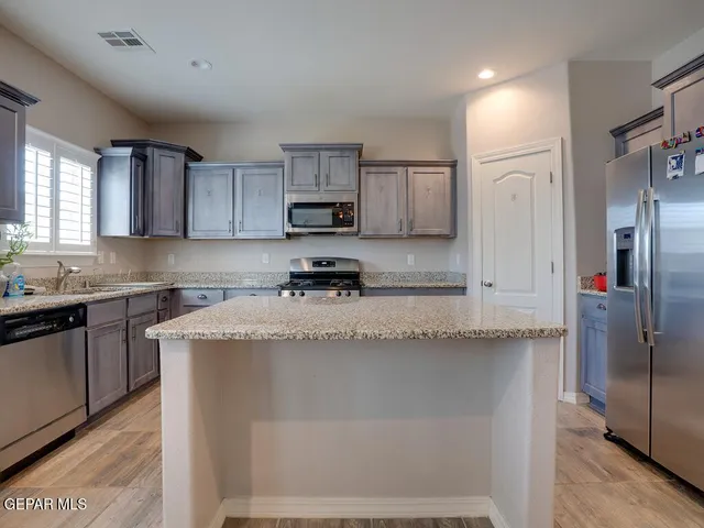 a kitchen with stainless steel appliances granite countertop a refrigerator a stove a sink and a granite counter tops