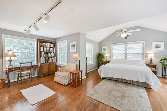 a spacious bedroom with a bed a couch and a bookshelf with wooden floor