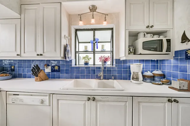 a kitchen with stainless steel appliances a sink a stove and white cabinets