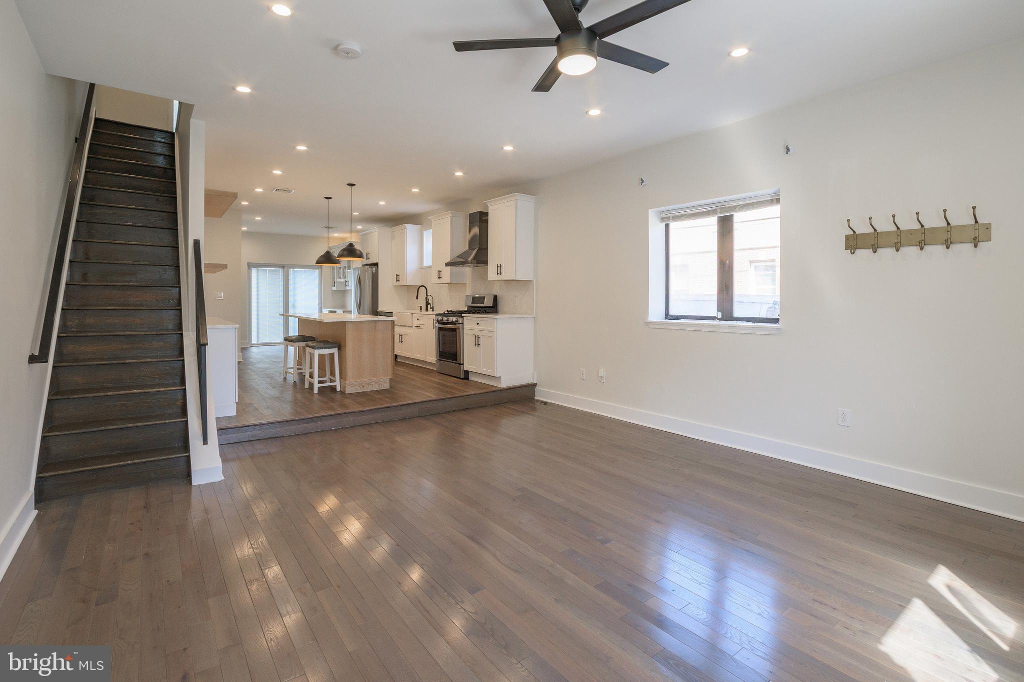 a view of a living room a ceiling fan and wooden floor