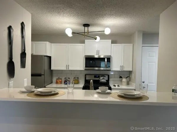 a kitchen with stainless steel appliances a sink a stove a microwave a refrigerator and cabinets