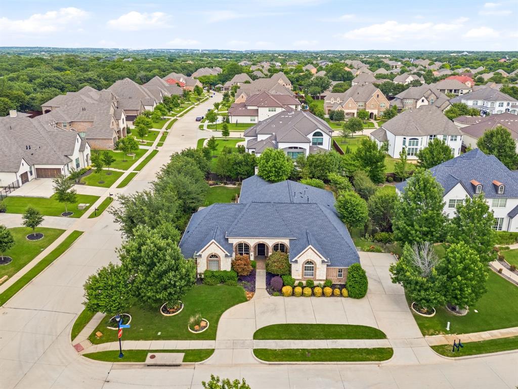 7013 Handel Colleyville, TX 76034 - Photo 2 of 37 Traditional-style home featuring a dark shingle roof, light-colored brick facade, arched entryways, and a concrete driveway