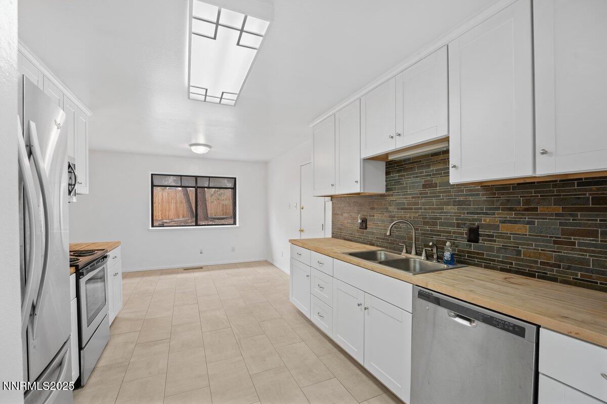 1421 Surf Way Reno, NV 89503 - Photo 11 of 30 a kitchen with stainless steel appliances granite countertop a stove a sink a refrigerator and white cabinets