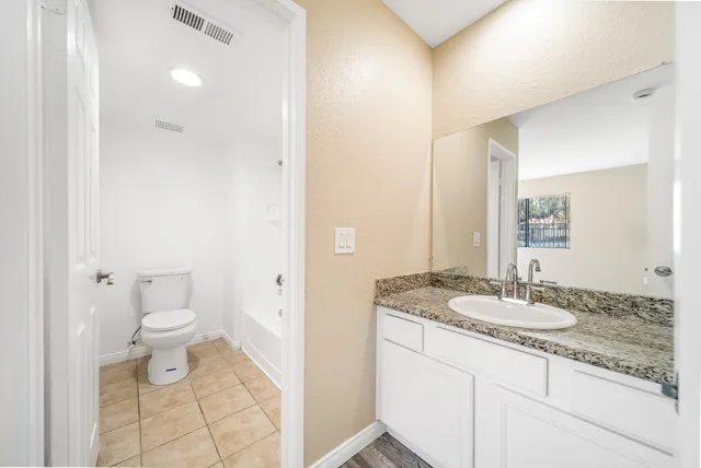 a bathroom with a granite countertop sink a toilet and a mirror
