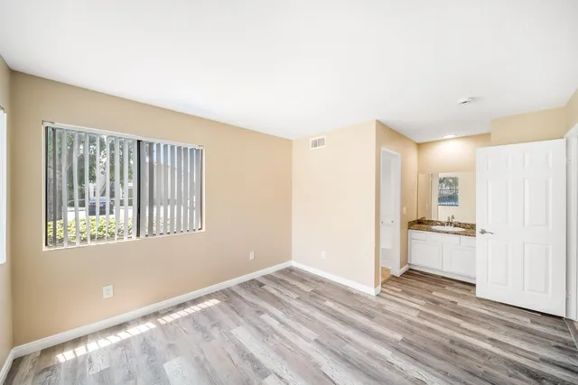 a view of an empty room with a window and wooden floor