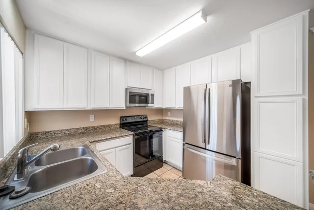 a kitchen with stainless steel appliances granite countertop a refrigerator sink and stove