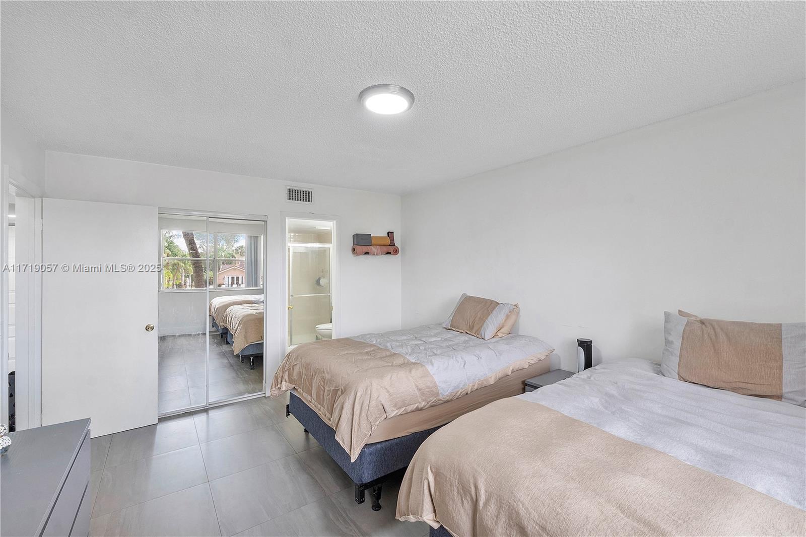 8871 Wiles Road, Unit 204 Coral Springs, FL 33067 - Photo 11 of 25 a bedroom with two beds and a lamp