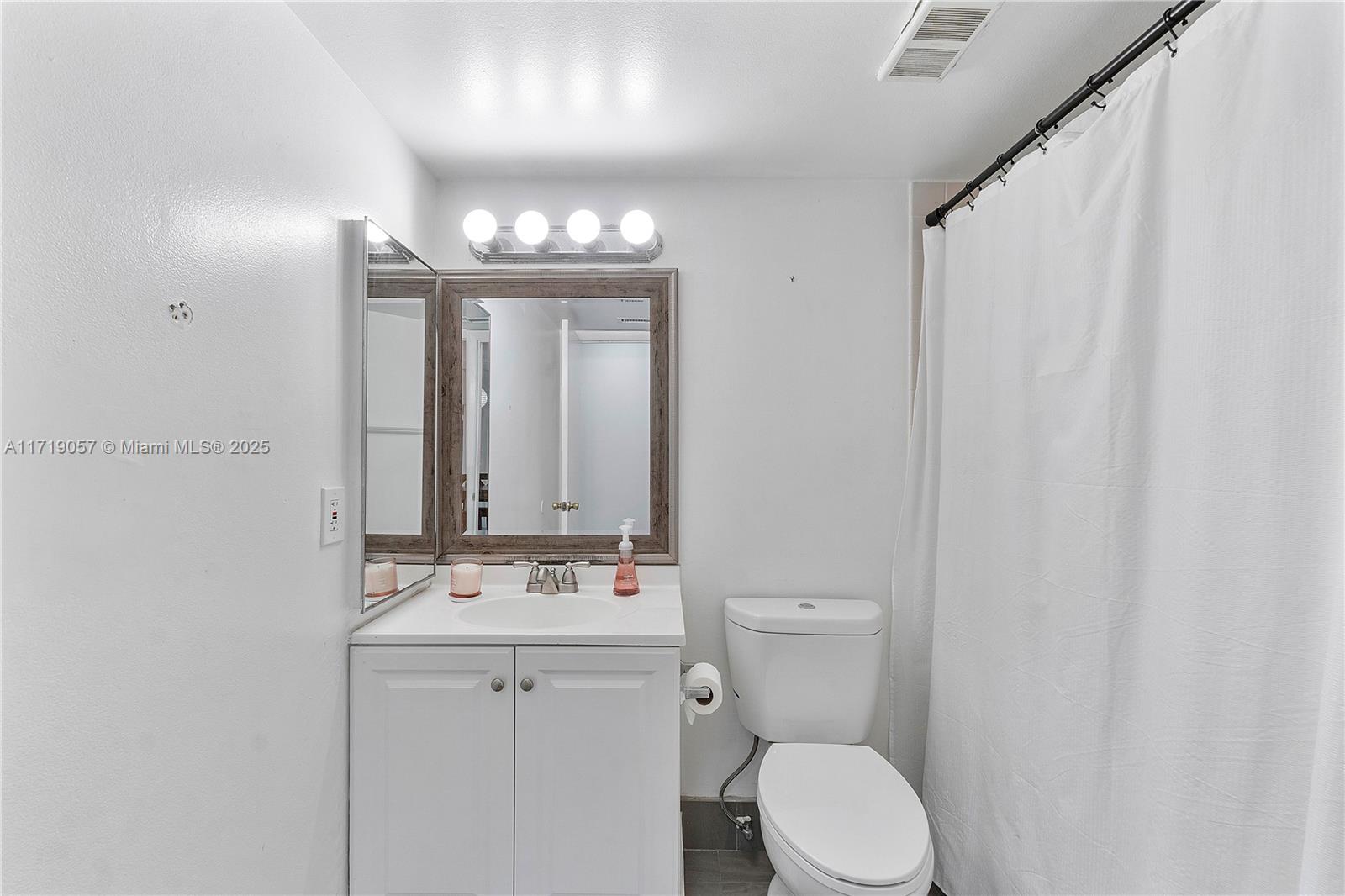 8871 Wiles Road, Unit 204 Coral Springs, FL 33067 - Photo 17 of 25 a bathroom with a toilet a sink and mirror