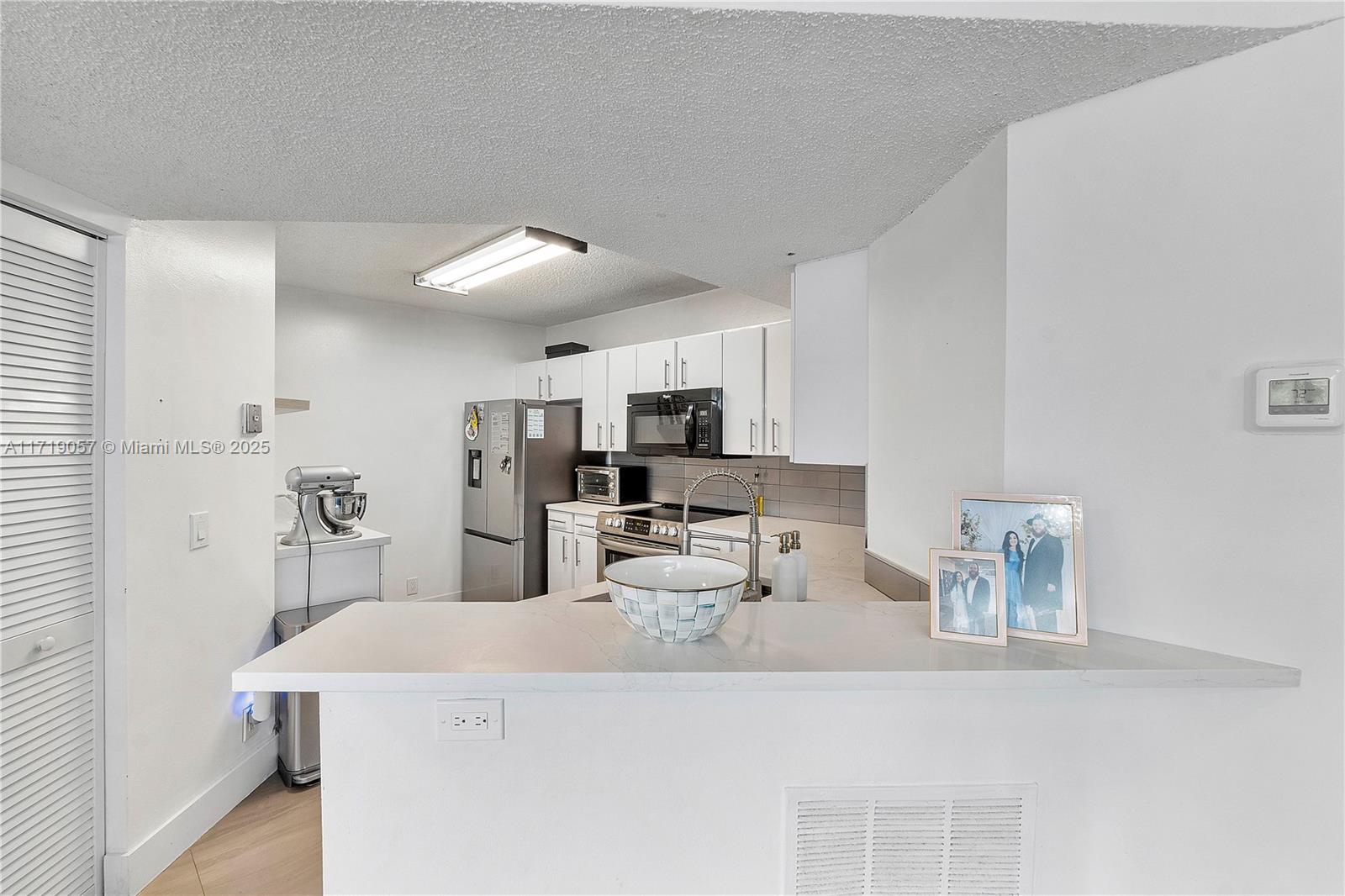 8871 Wiles Road, Unit 204 Coral Springs, FL 33067 - Photo 4 of 25 a kitchen with stainless steel appliances kitchen island sink refrigerator and microwave