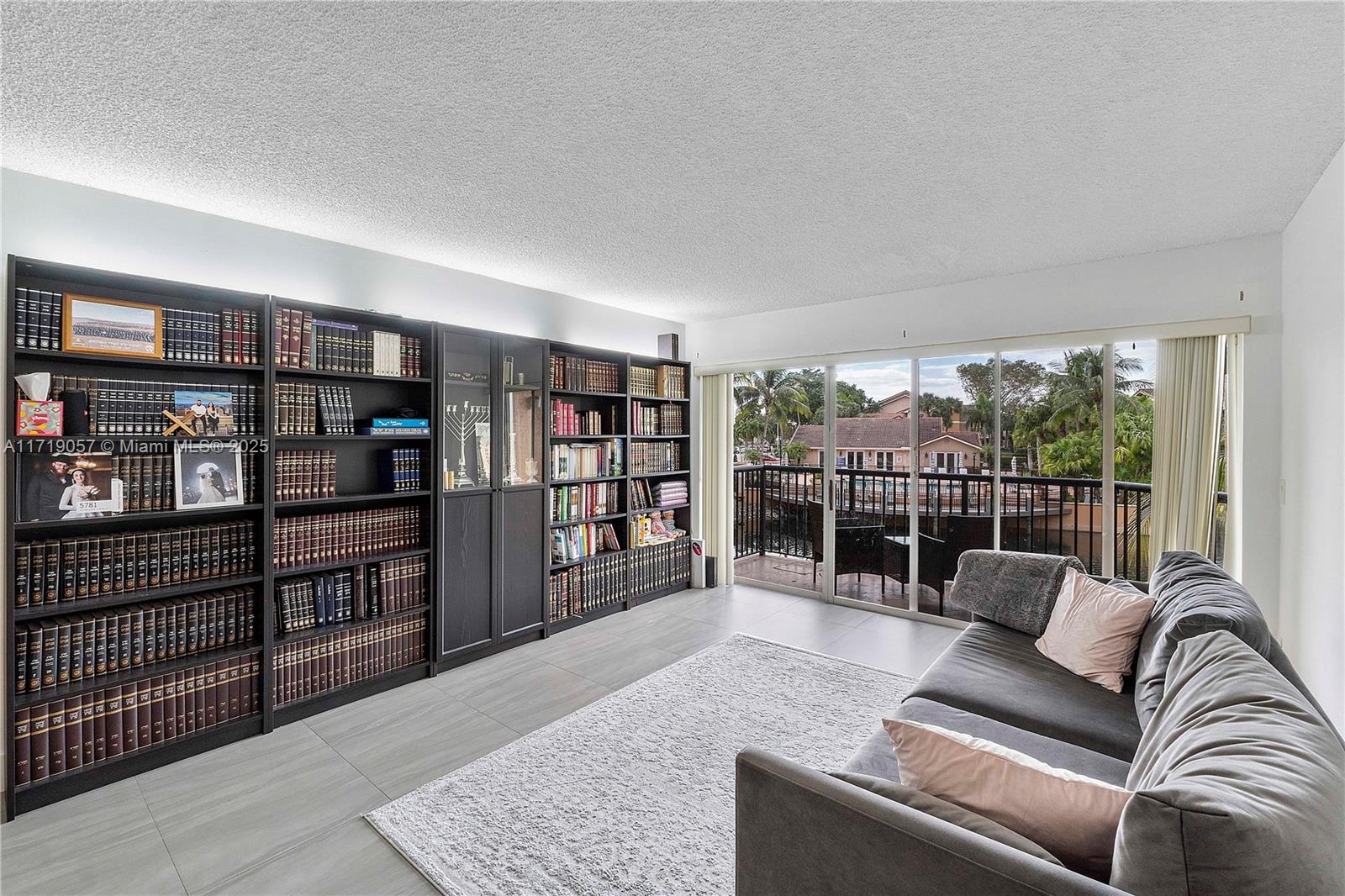 8871 Wiles Road, Unit 204 Coral Springs, FL 33067 - Photo 10 of 25 a living room with furniture a rug and a book shelf