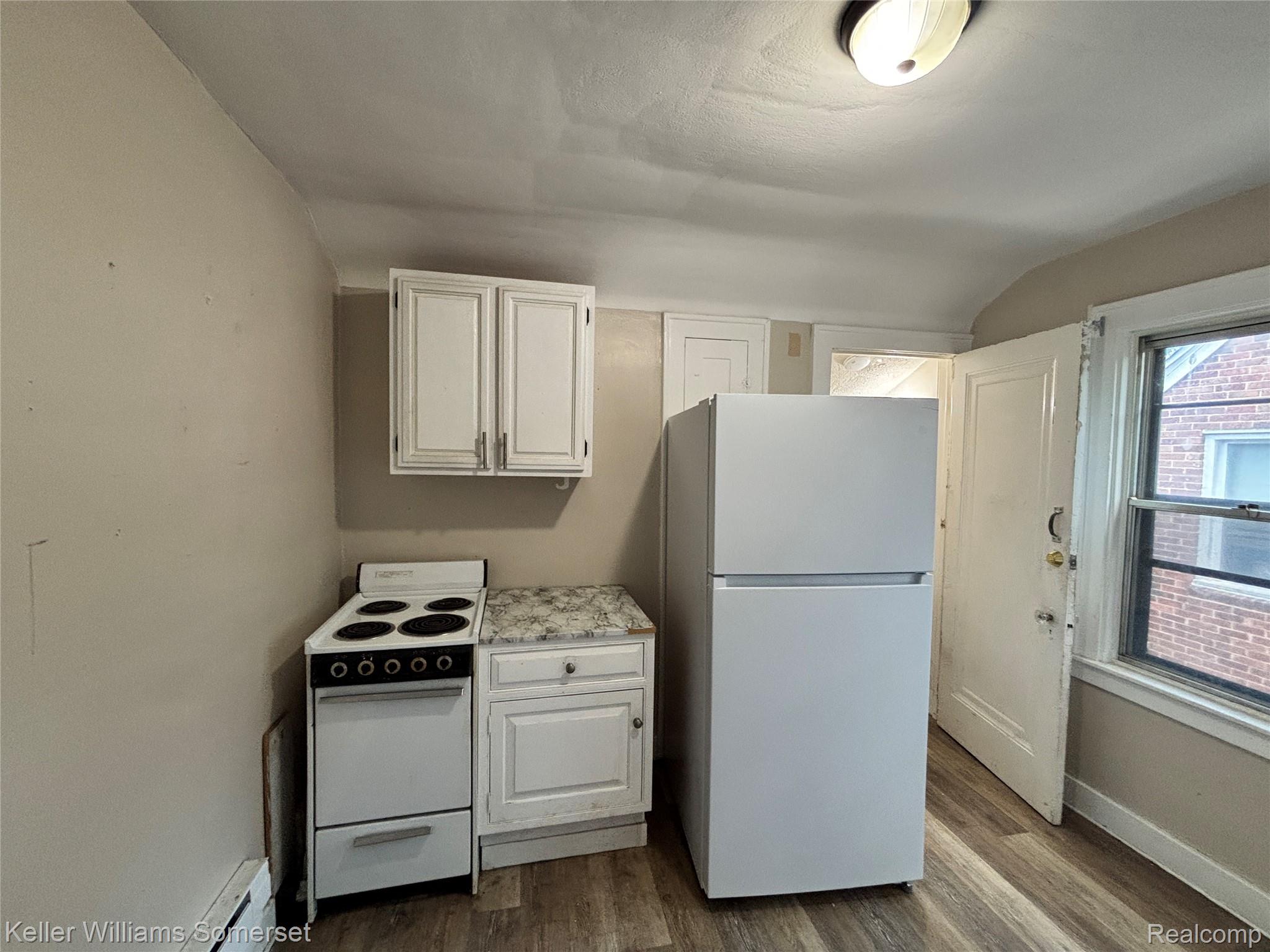 5783 Yorkshire Road Detroit, MI 48224 - Photo 3 of 13 Compact kitchen with wood-finish flooring, white cabinetry, a freestanding refrigerator, a four-burner electric range, and a window providing natural illumination