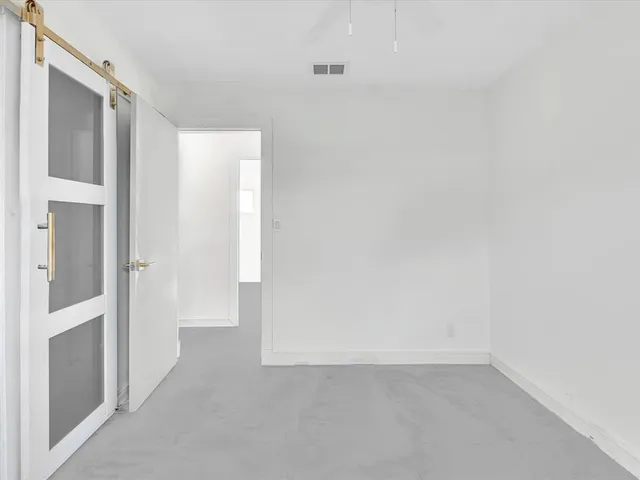 a view of a white house in front of a yard with plants and large trees