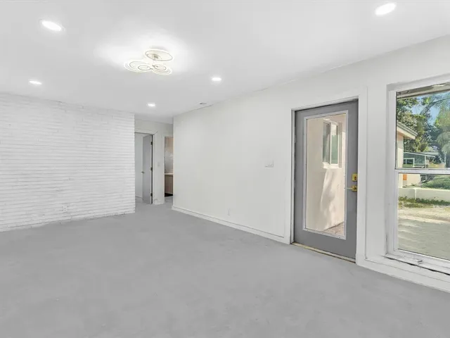 an empty room with windows and fireplace