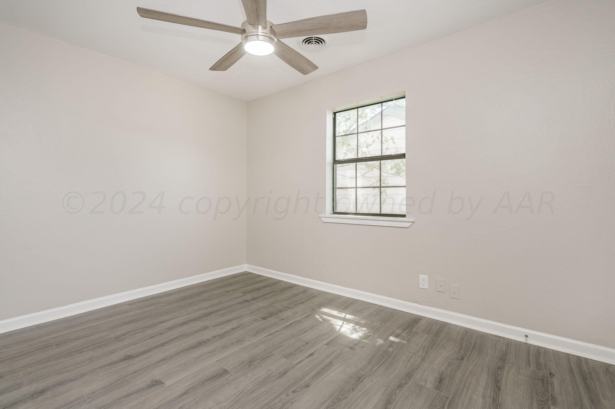 4013 South Jackson Street Amarillo, TX 79110 - Photo 11 of 18 an empty room with wooden floor chandelier fan and windows