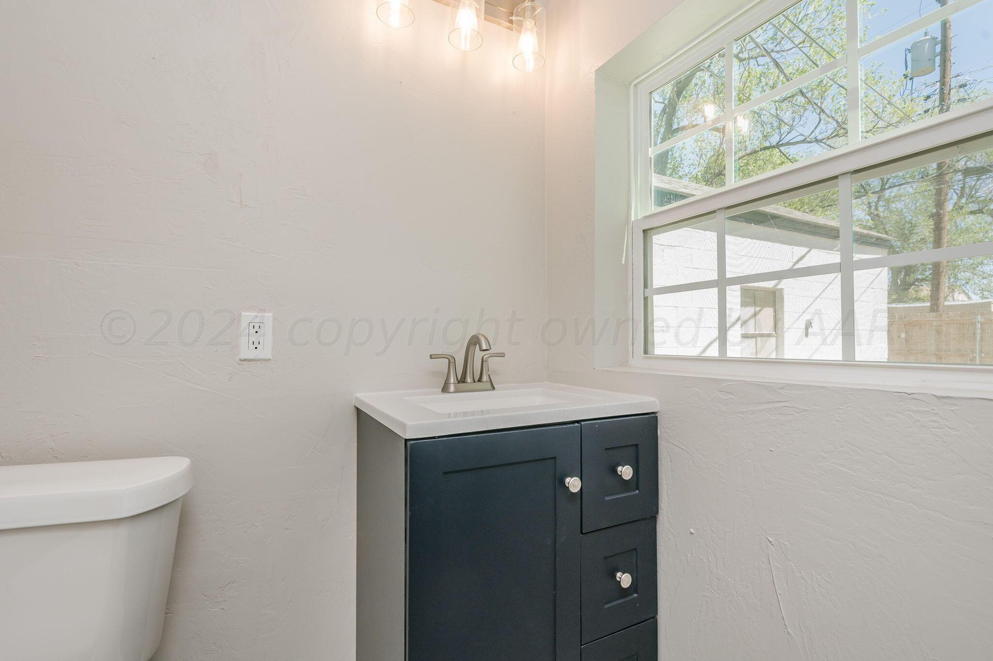 4013 South Jackson Street Amarillo, TX 79110 - Photo 14 of 18 a bathroom with a sink a toilet and a window