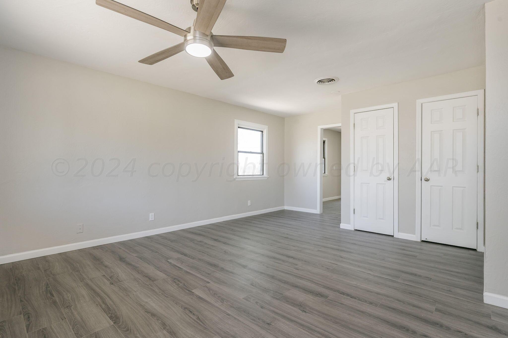 4013 South Jackson Street Amarillo, TX 79110 - Photo 7 of 18 an empty room with wooden floor ceiling fan and windows