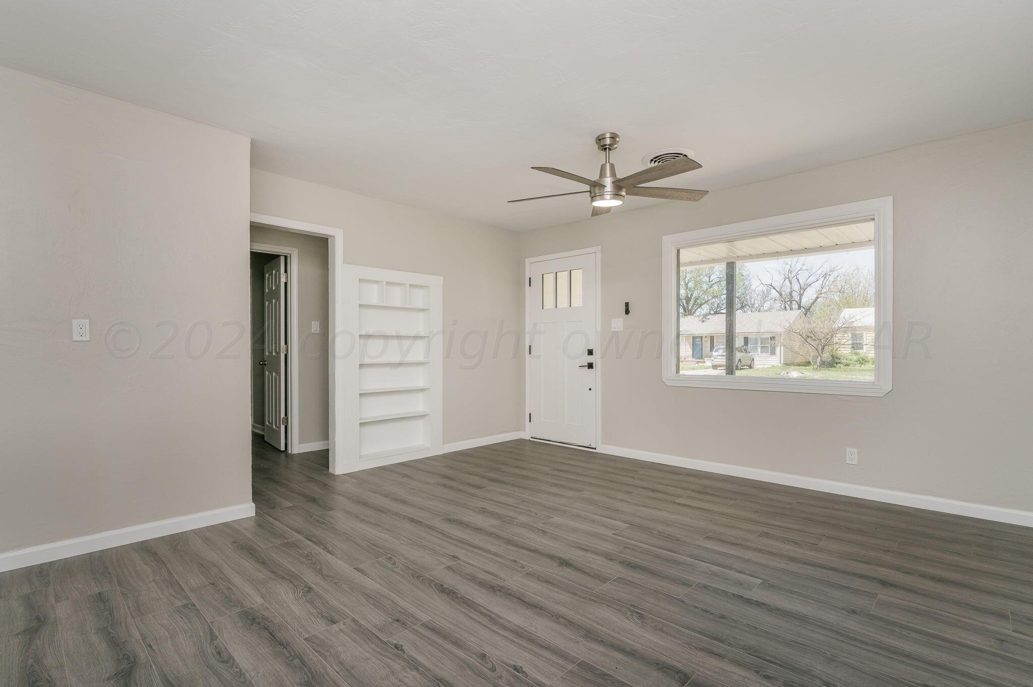 4013 South Jackson Street Amarillo, TX 79110 - Photo 8 of 18 an empty room with wooden floor chandelier fan and windows