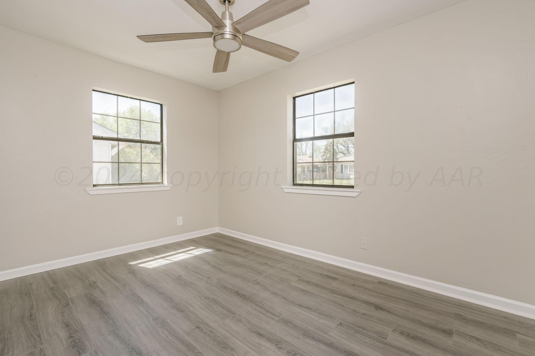 4013 South Jackson Street Amarillo, TX 79110 - Photo 9 of 18 an empty room with wooden floor windows and fan
