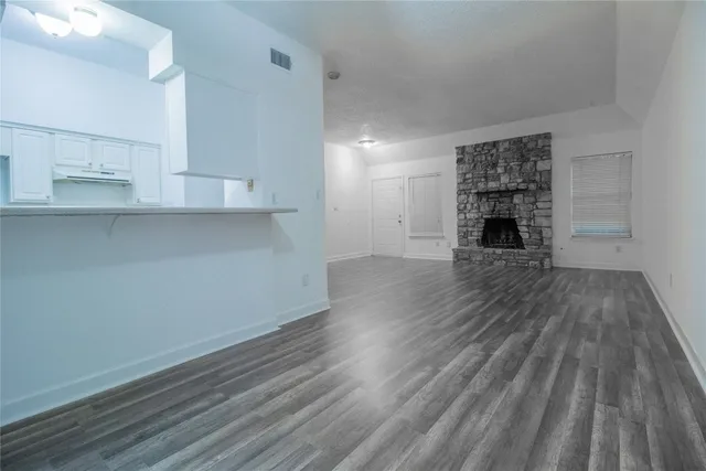 an empty room with wooden floor a cabinet and windows