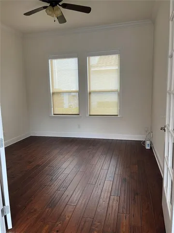 an empty room with wooden floor closet and windows