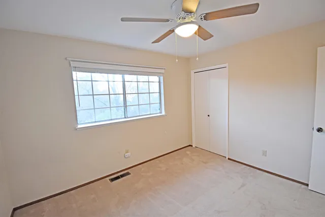 an empty room with a window and a fan