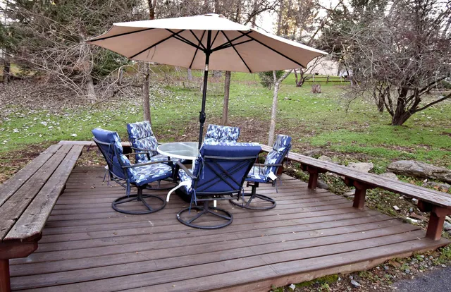 a view of a patio with table and chairs with wooden floor and fence