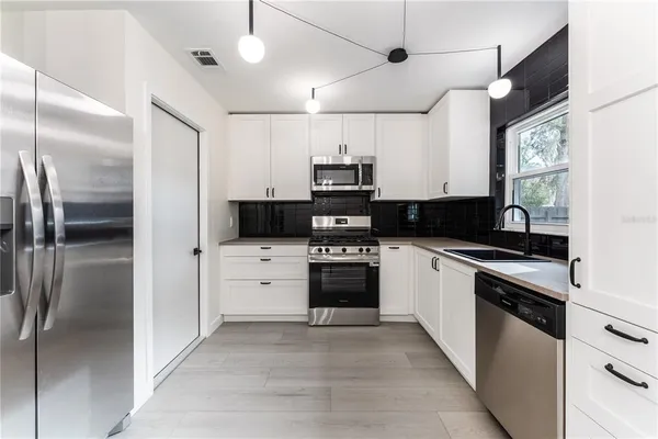 a kitchen with a refrigerator and white cabinets