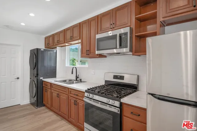 a kitchen with stainless steel appliances granite countertop a stove microwave refrigerator and sink