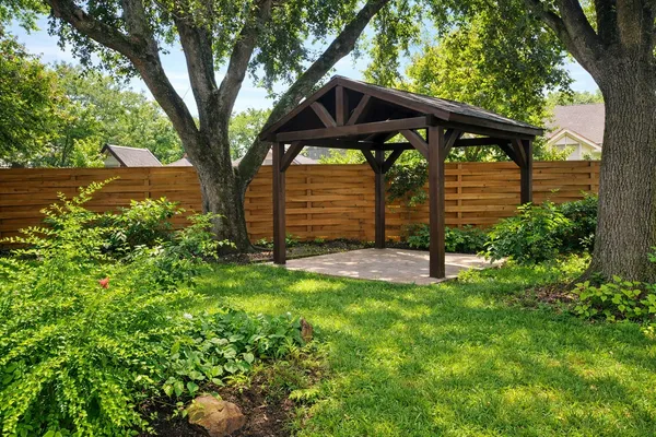 a view of a backyard with a shade house and large tree