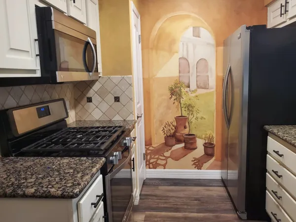 a kitchen with stainless steel appliances granite countertop a stove a refrigerator and wooden cabinets