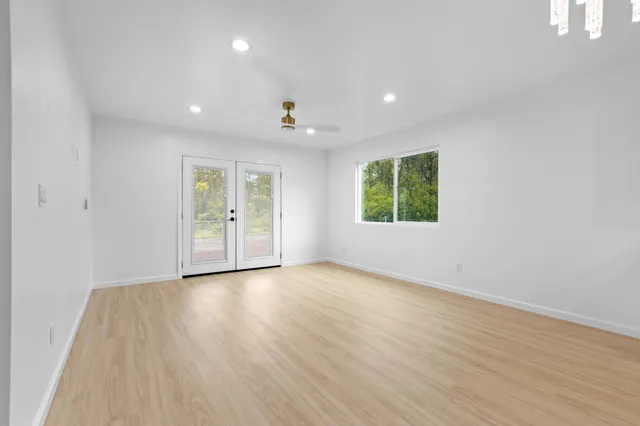 an empty room with wooden floor and windows