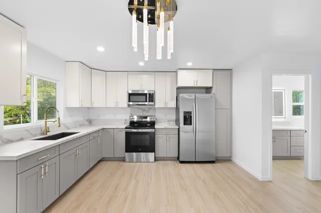 a kitchen with stainless steel appliances a sink a stove a refrigerator cabinets and a window