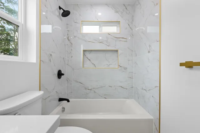 a bathroom with a bathtub window and toilet