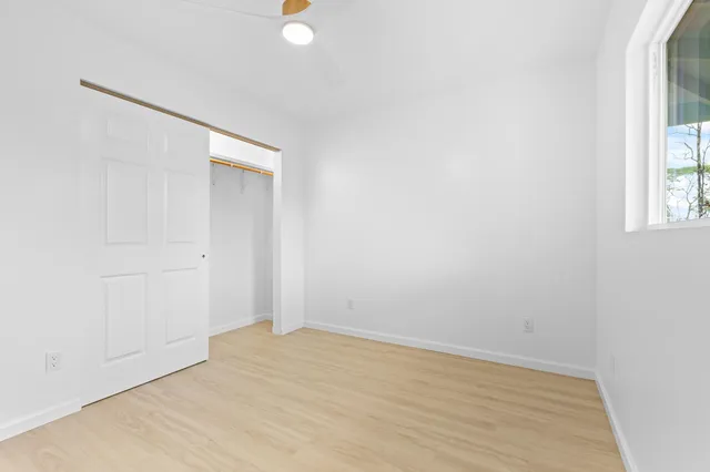 an empty room with wooden floor and windows