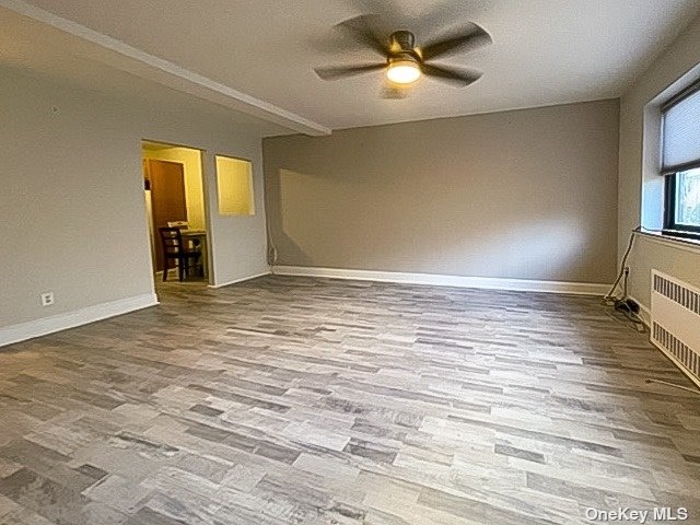 a view of an empty room with window and wooden floor
