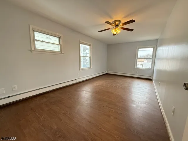 an empty room with wooden floor and windows with curtains