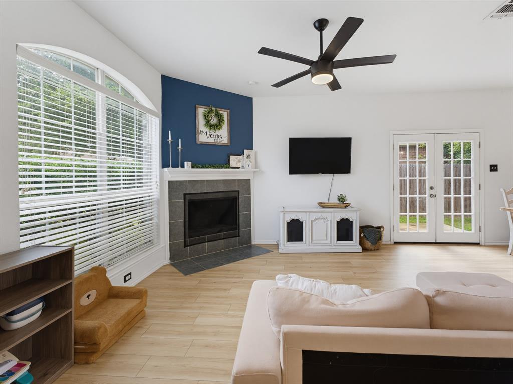 600 Stirling Road Rhome, TX 76078 - Photo 2 of 38 Spacious living area featuring light wood-finish flooring, a contemporary ceiling fan, and an arched window with blinds