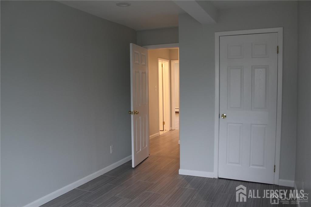 899 Green Street, Unit 1ST F Iselin, NJ 08830 - Photo 5 of 8 a view of an empty room with wooden floor and a window