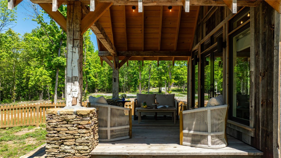 425 Barnhardt Road Timbo, AR 72680 - Photo 57 of 60 Covered wood deck featuring exposed beam construction, a stone-clad support column, plank flooring, and a natural wood ceiling