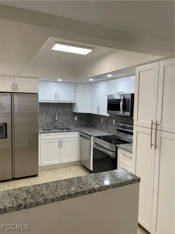 a kitchen with stainless steel appliances granite countertop a refrigerator a stove and a sink