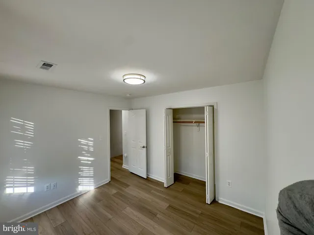 an empty room with wooden floor & closet and windows