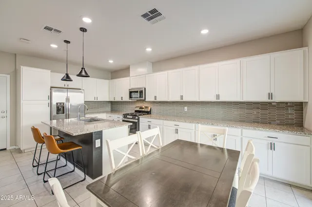 a kitchen with granite countertop cabinets and chairs in it