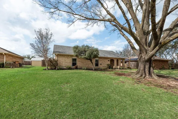 a view of a yard in front of a house with large trees