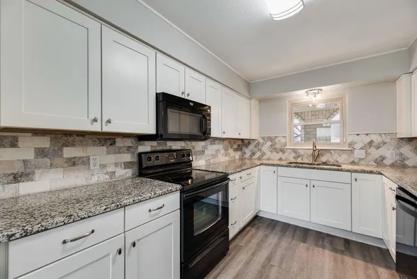 a kitchen with granite countertop white cabinets and white appliances