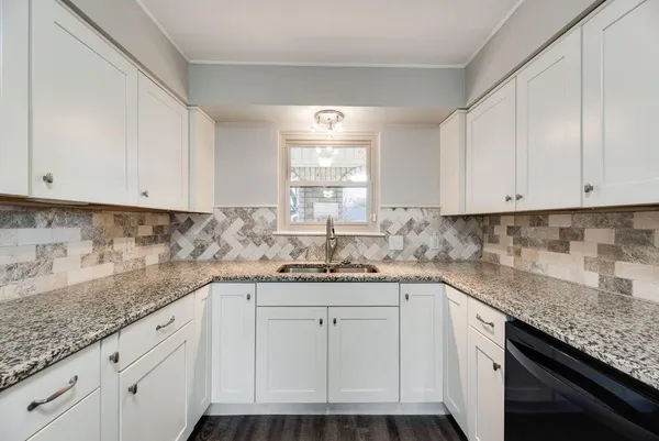 a kitchen with granite countertop cabinets stainless steel appliances and a wooden floor