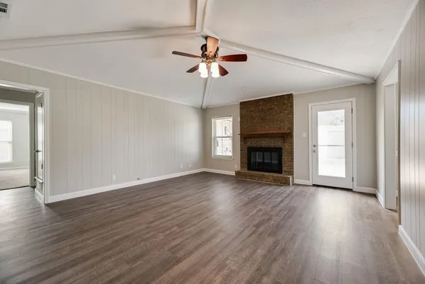 an empty room with wooden floor chandelier fan and windows