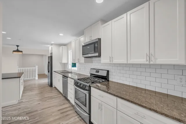 a kitchen with granite countertop a stove and a microwave