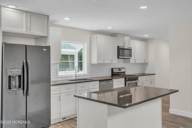 a kitchen with stainless steel appliances granite countertop a sink a stove and a wooden floors